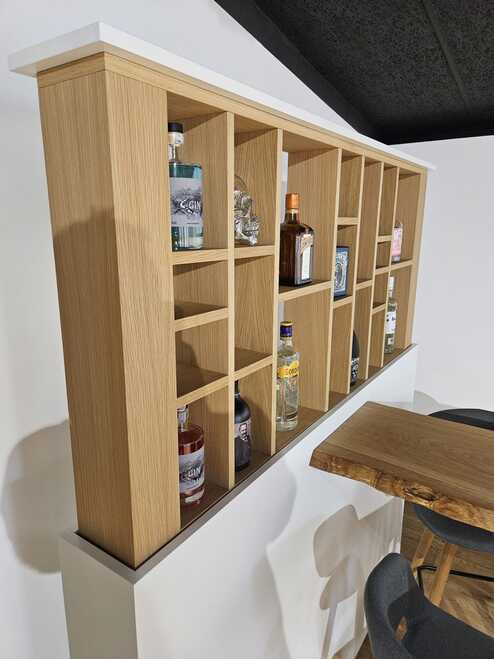 Individuell angefertigtes Regal nach Mass aus Holz mit offenen F&auml;chern f&uuml;r Flaschen und Deko, integriert in eine moderne Bar-Umgebung.