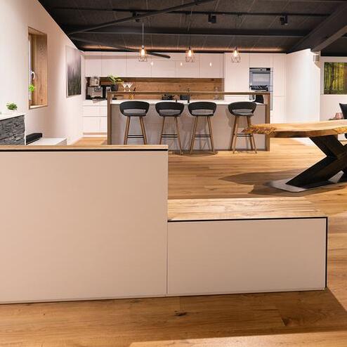 Wohn- und Essbereich mit modernem Möbel- und Küchendesign Offener Wohn- und Essbereich mit motorisierten Möbeln in Weiss- und Holzdesign, Massivholztisch, moderner Küche und warmem Holzfussboden.