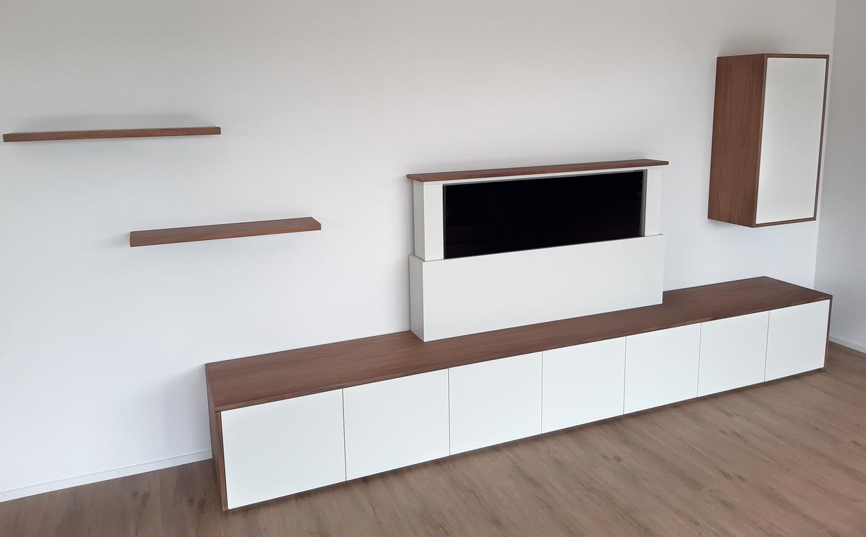Modernes Sideboard mit integriertem, motorisiert ausfahrbarem Fernseher und passenden Wandregalen.