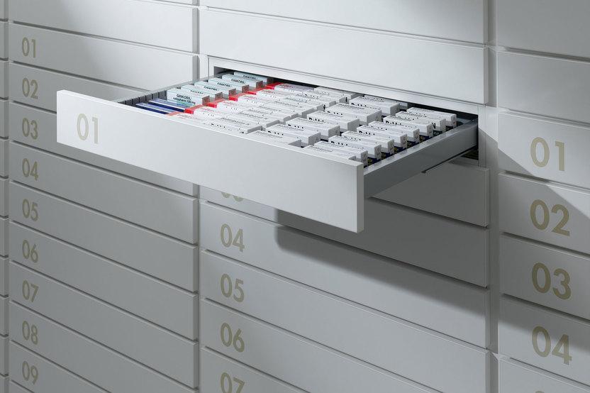 Detailaufnahme von schmalen weissen Medikamentenschubläden mit dezenter Nummerierung und sichtbarer Medikamentenaufteilungen.