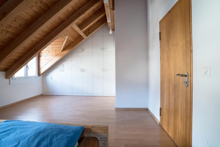 Nischenlösung für Einbauschrank an holzbelassener Dachschräge Nischenlösung für weissen Einbauschrank mit Schubladen und Türen an in dunklem Holz belassener Dachschräge