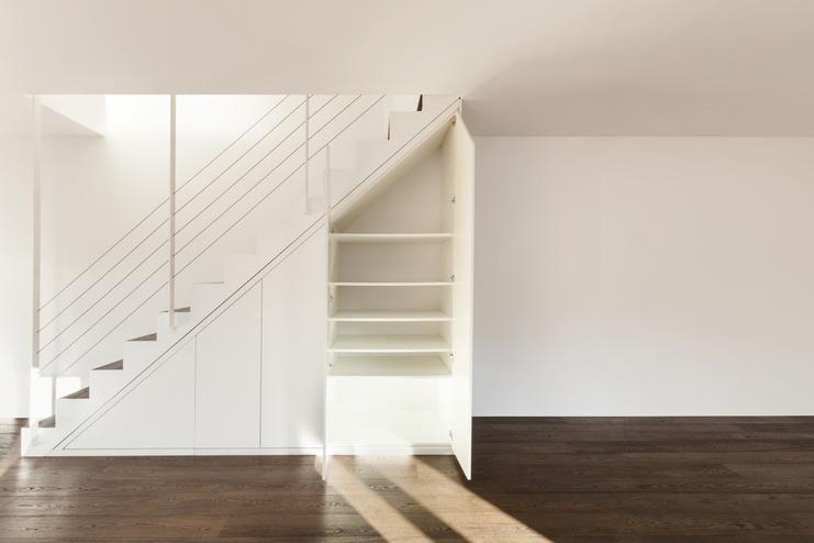 Nischenlösung für Einbauschrank unter Treppe Geräumiger Einbauschrank unter weisser Treppe mit Schubläden und Türen und offener Regalgestaltung an dunklem Parkett