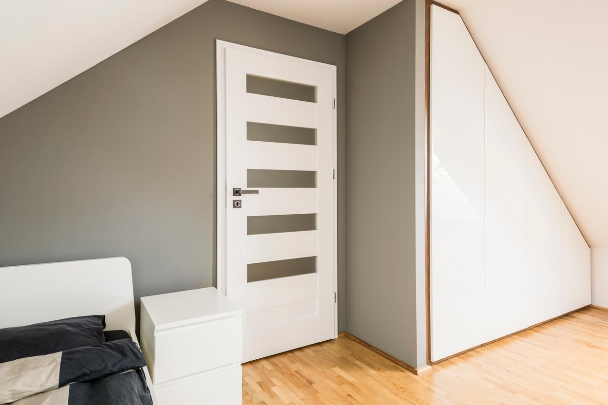 Weisser Einbauschrank an Dachschräge Weisser Einbauschrank an Dachschräge, dreieckig mit Trennwand zur Zimmertür an hellem Parkett.