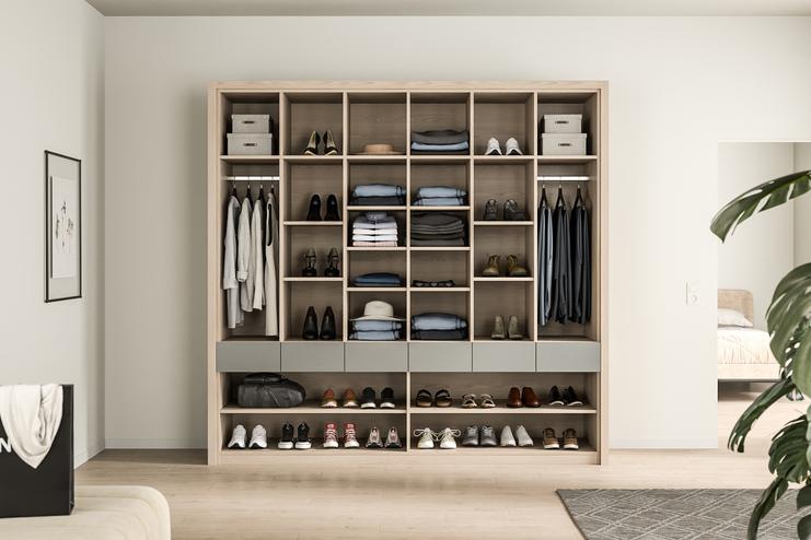 Ein auf Mass gefertigter, strukturierter Kleiderschrank, der Kleidung und Schuhe übersichtlich präsentiert, mit Holzakzenten.