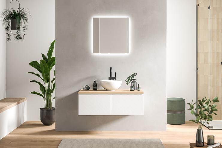 Minimalistisch designtes Bad nach Mass mit schwebendem Waschtisch in Weiss, beleuchtetem Spiegel und grünen Pflanzendetails.