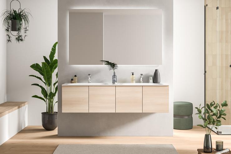 Ein schickes Bad nach Mass mit einem hellen Holzwaschtisch, Doppelwaschbecken und einer grossen Spiegelfläche, umgeben von grüner Zimmerpflanze.