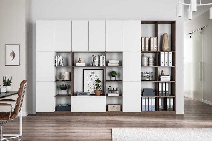 Ein multifunktionaler Wandschrank nach Mass, weiss, mit offenen Regalen für Bücher und Deko, fügt sich in ein modernes Zimmer ein.