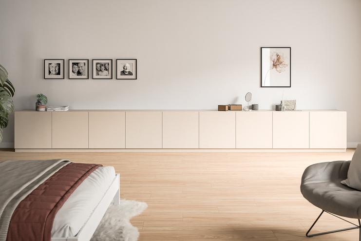Niedriges, massgefertigtes Sideboard in Creme, unter einer Wandgalerie aus Familienfotos, ergänzt durch minimalistische Dekoration.