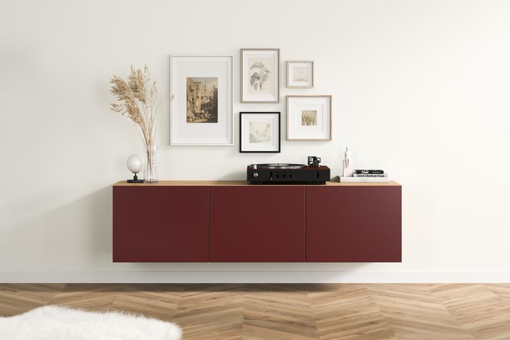 Elegantes, burgunderrotes Hängeboard nach Mass mit glatten Fronten und Holzakzenten, angebracht unter einer kunstvollen Bildergalerie im Wohnzimmer.