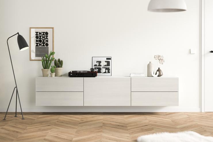 Ein massangefertigtes, wandmontiertes Hängeboard in schlichtem Weiss, ergänzt durch zeitgenössische Deko und Grünpflanzen, fügt sich nahtlos in ein gemütliches Wohnambiente ein.