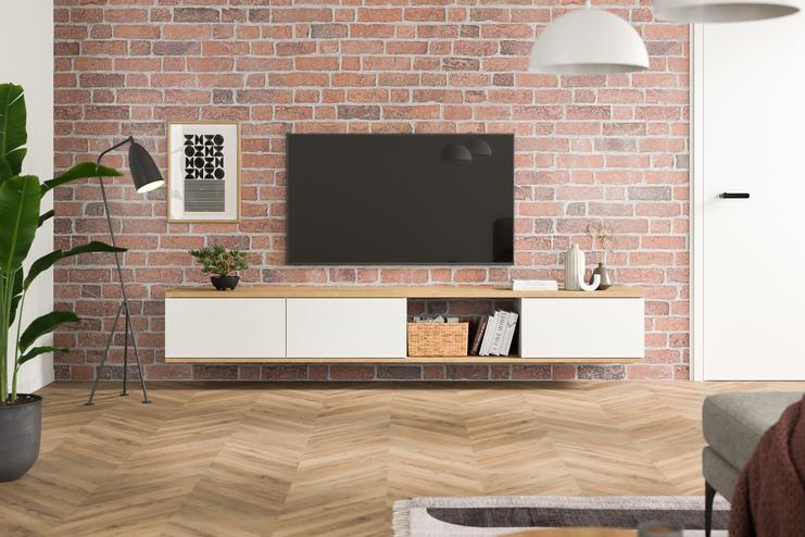 Massangefertigtes Hängeboard in Weiss, minimalistisch gestaltet, unter einem Wandfernseher, vor einer roten Backsteinwand, ergänzt durch Pflanzen und Bücher.