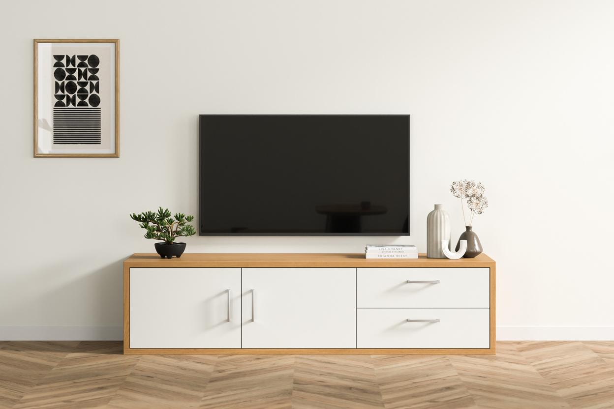 Elegante Kommode nach Mass im stilvollen Wohnzimmer Eine massgeschneiderte Kommode in hellem Holzfinish mit weissen Fronten, darunter ein TV-Gerät, begleitet von dekorativen Vasen und Büchern, in einem hellen Wohnraum.
